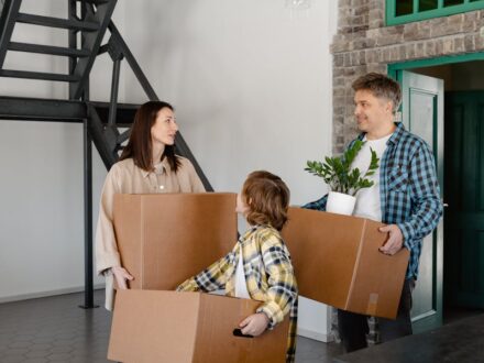 A happy family carrying boxes inside their new home, capturing the joy of moving in.