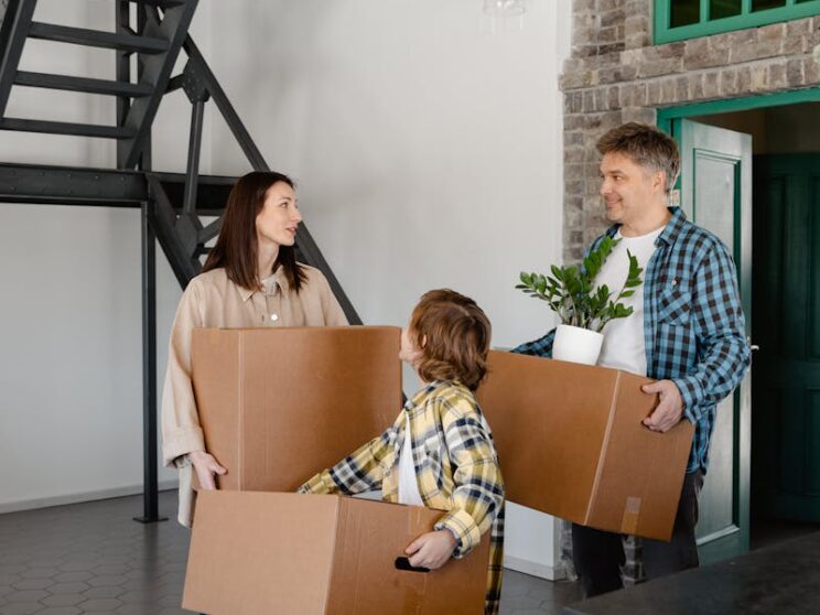 A happy family carrying boxes inside their new home, capturing the joy of moving in.